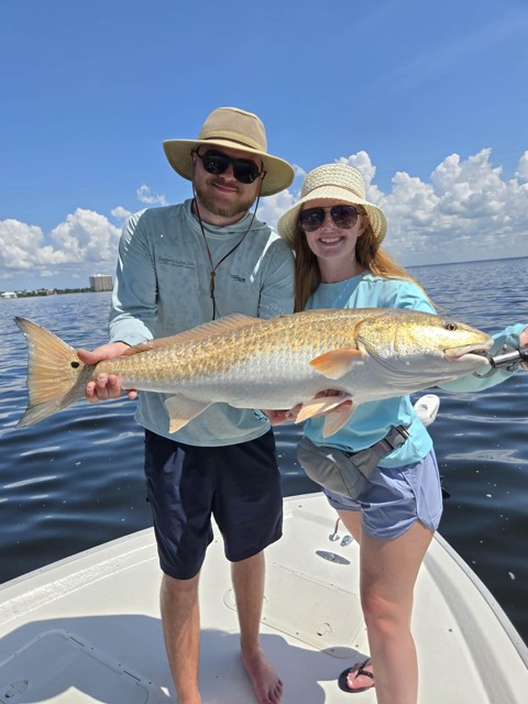 Two guests holding a redfish during a South Walton fishing trip